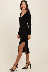 woman wearing a black ribbed midi dress with a side slit and long sleeves, paired with black heeled sandals