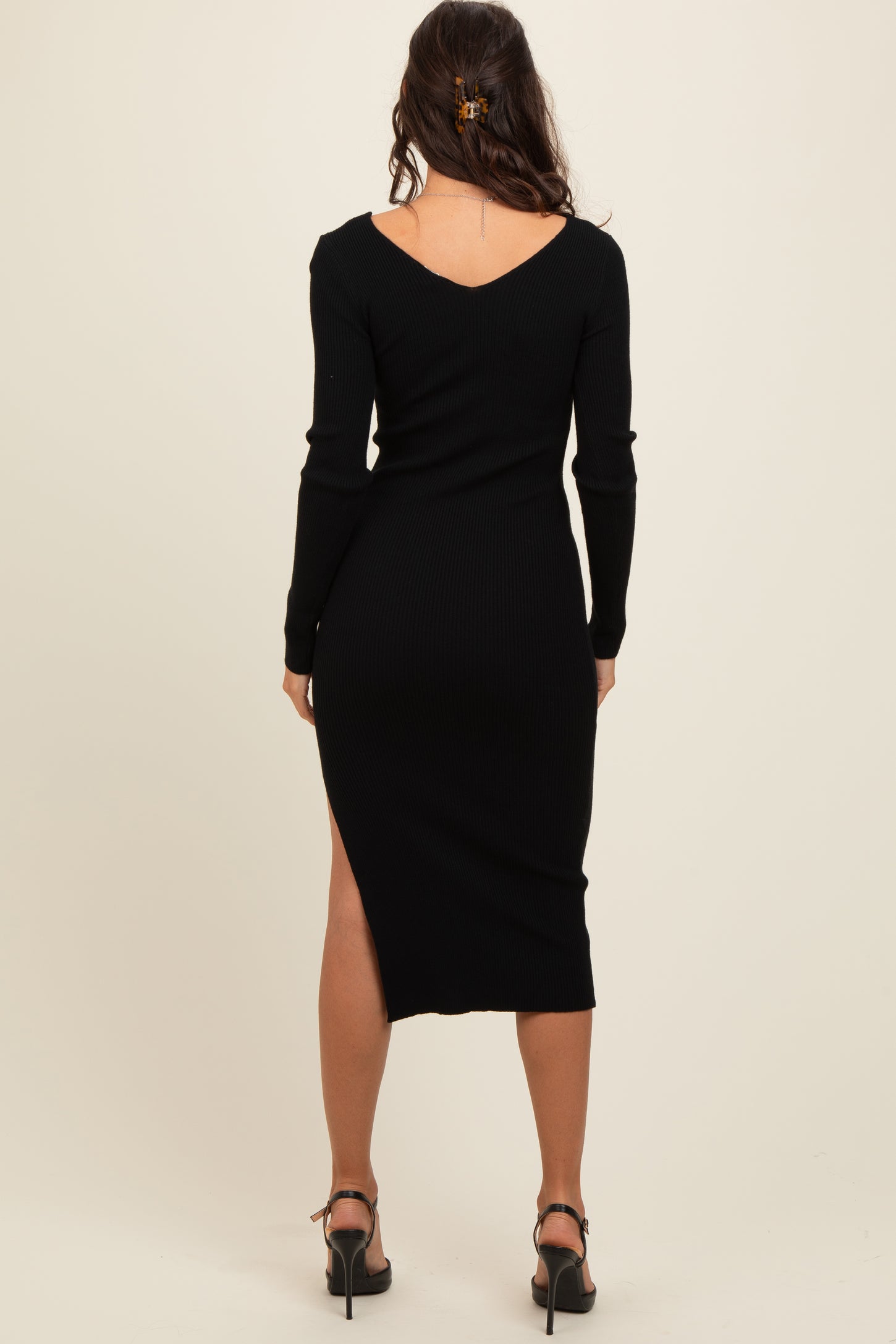 woman wearing a black ribbed midi dress with a deep v-back and side slit, shown from the back