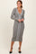 woman wearing a grey ribbed midi dress with a deep v-neck and contrasting white button detailing