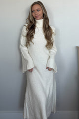 woman wearing a white long sleeve turtleneck dress with bell sleeves and a maxi length