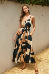woman wearing a patterned maxi dress with spaghetti straps and pockets, featuring a tie waist detail