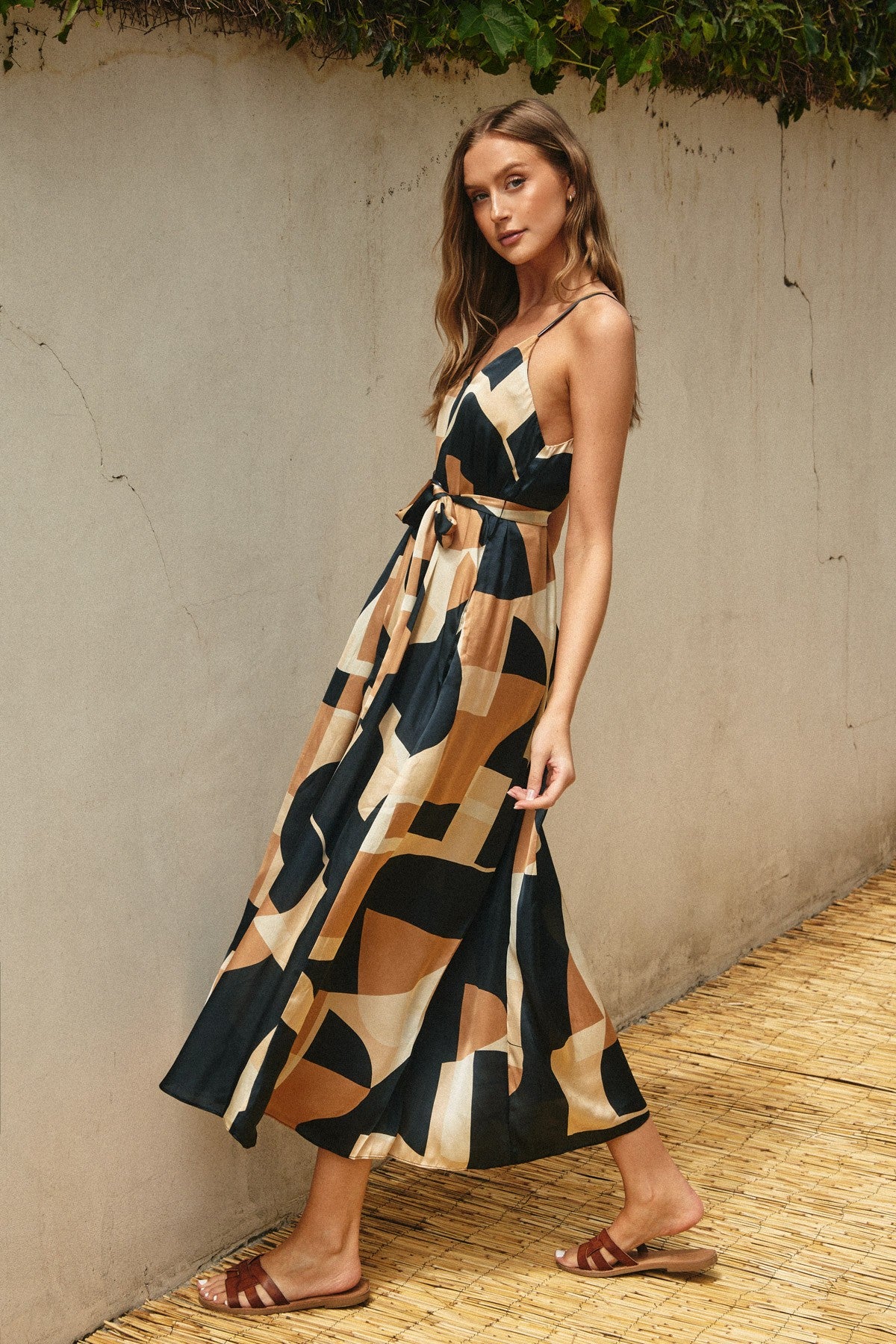 woman wearing a navy blue and tan patterned maxi dress with a tie waist and spaghetti straps