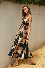 woman wearing a navy blue and tan patterned maxi dress with a tie waist and spaghetti straps