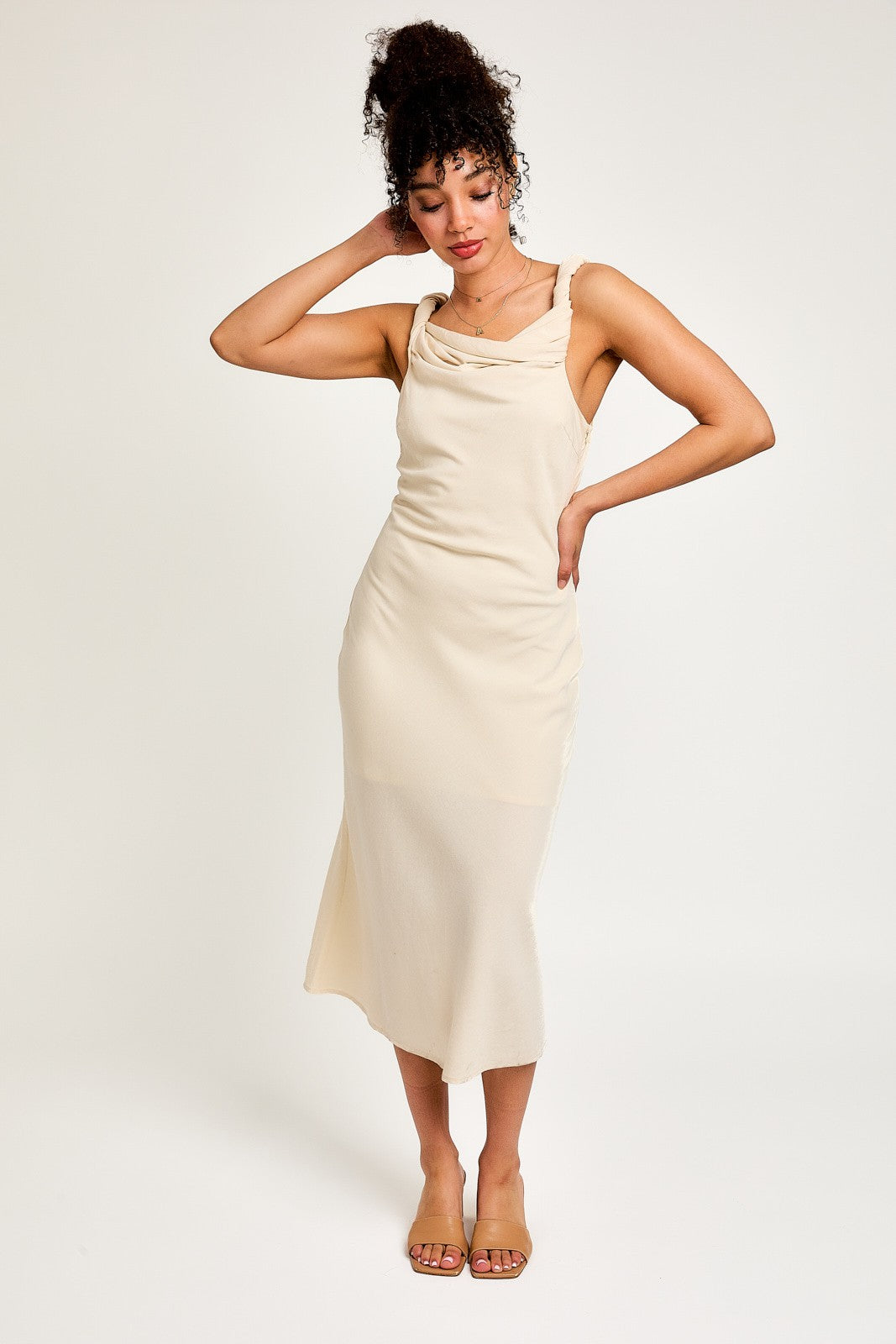 woman wearing a cream sleeveless midi dress with a draped neckline and a relaxed fit