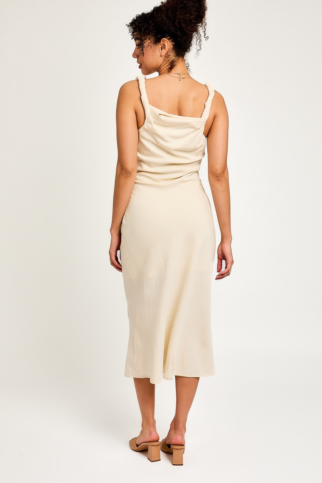 woman wearing a beige midi dress with adjustable straps and a relaxed fit, viewed from the back