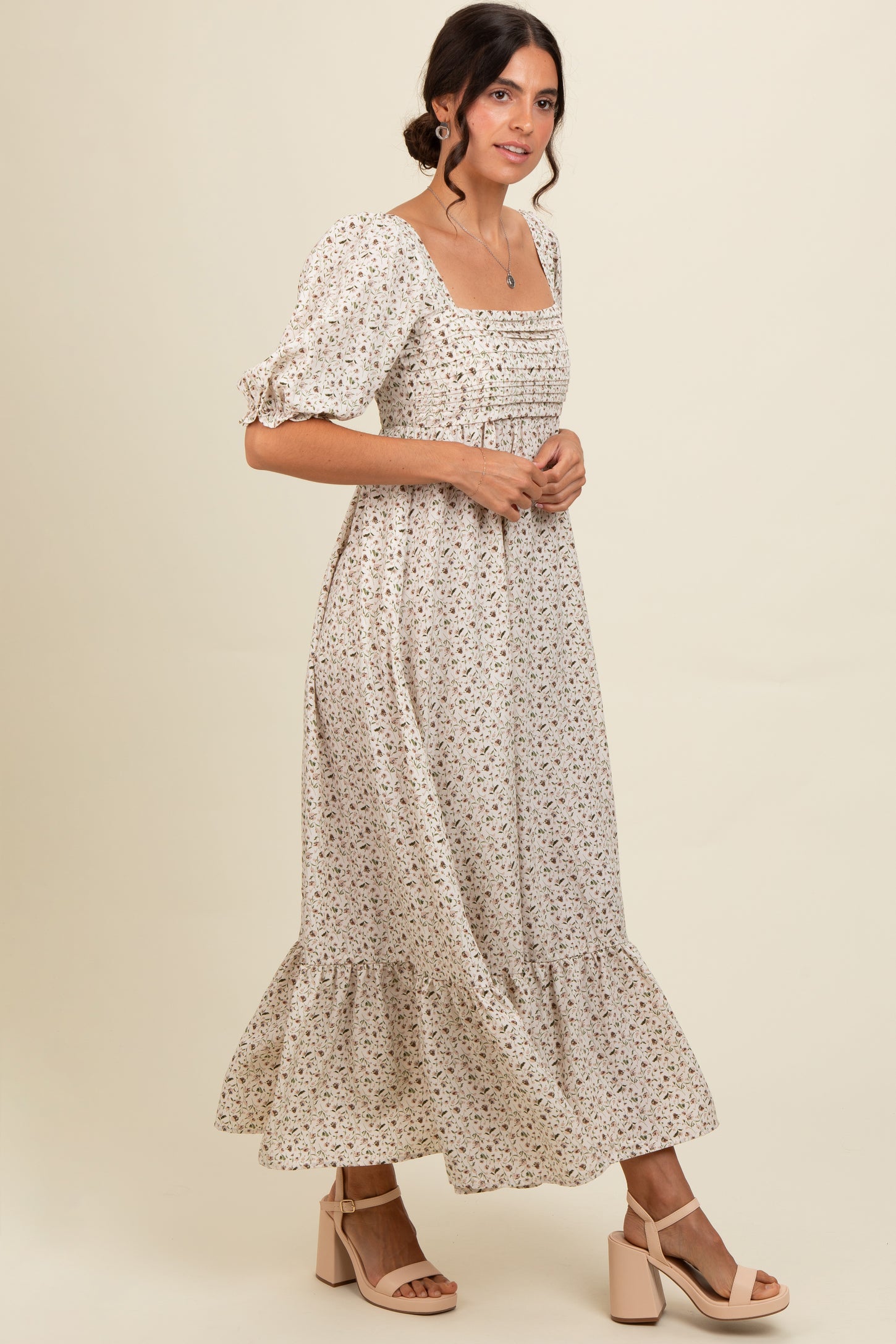 woman wearing a cream floral maxi dress with puff sleeves and a square neckline