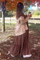 woman wearing a brown floral maternity maxi dress with a cream cardigan and holding a coffee cup, baby bump visible