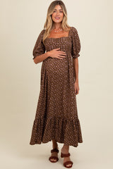 woman wearing a brown floral maternity dress with puff sleeves and a ruffled hem, holding her baby bump