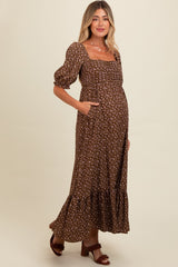 woman wearing a brown floral maternity maxi dress with puff sleeves and pockets, showcasing her baby bump
