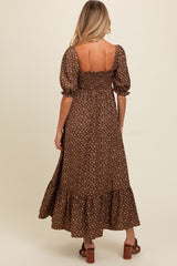 woman wearing a brown floral maternity maxi dress with puff sleeves and a smocked bodice, showing her back and flowing skirt