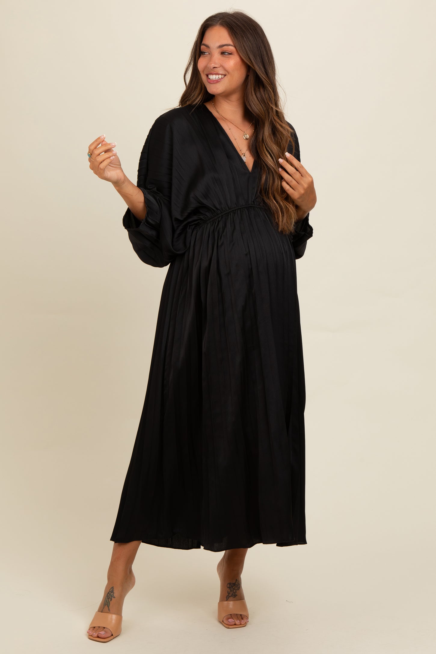 woman wearing a black maternity dress with a deep v-neck and gathered waist, showcasing her baby bump