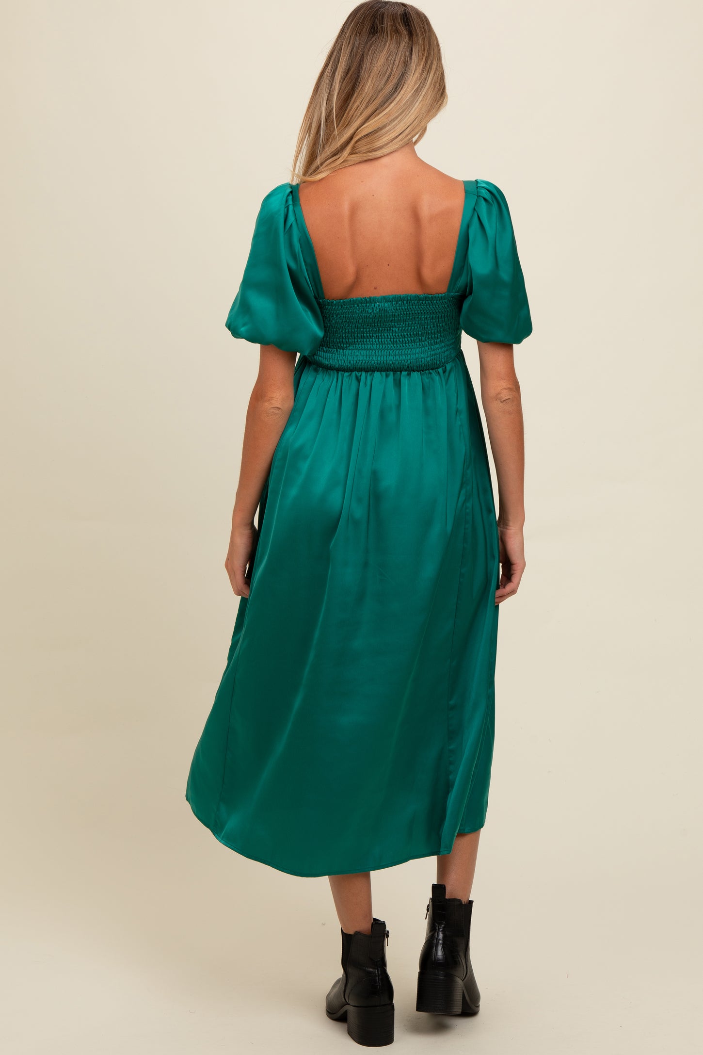 woman wearing a green satin maternity dress with puff sleeves and a smocked back, shown from the back