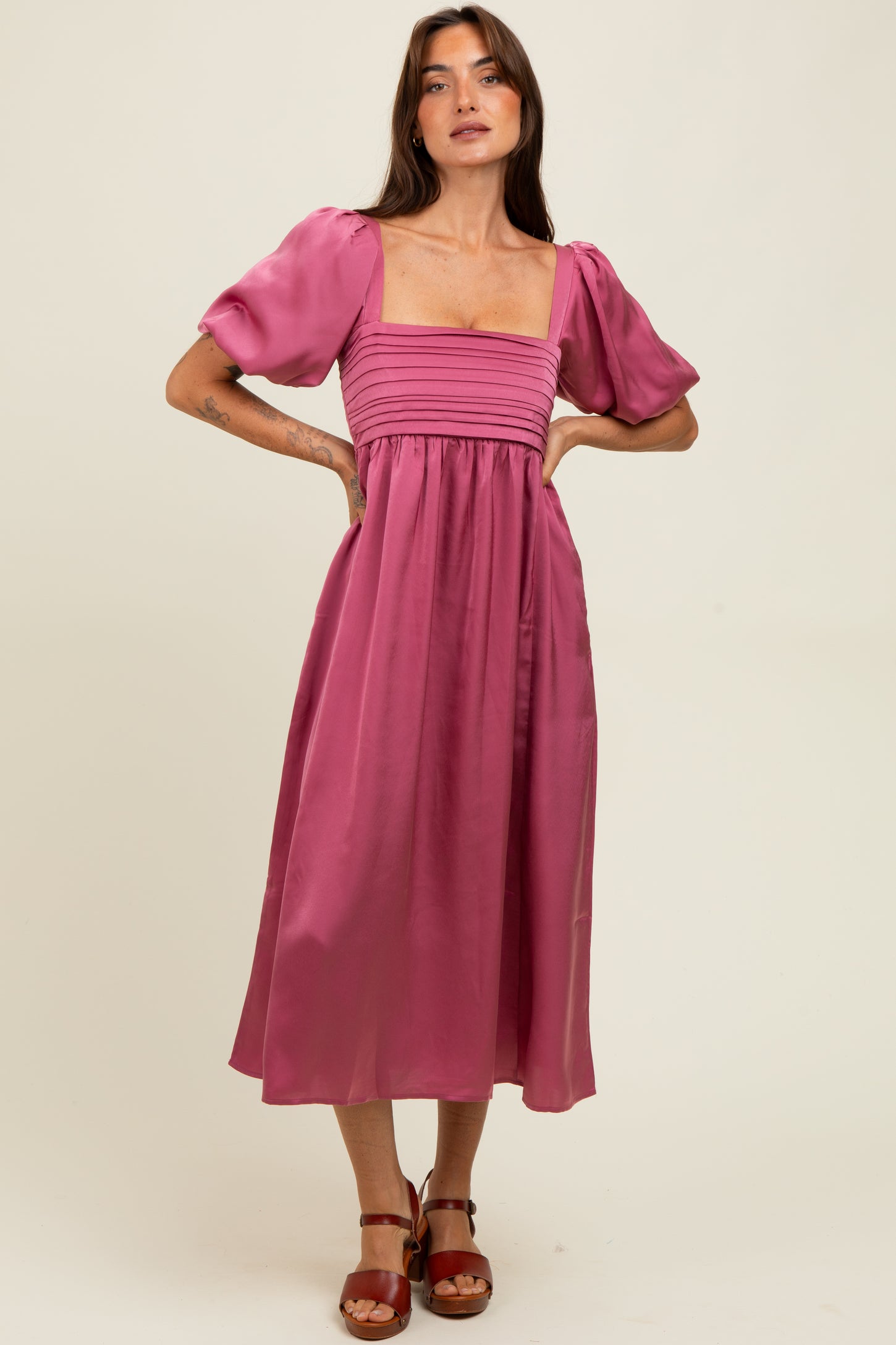 woman wearing a fuchsia puff sleeve midi dress with a square neckline and gathered details