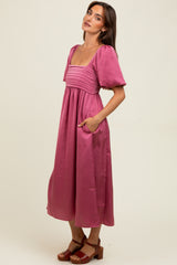 woman wearing a pink puff sleeve midi dress with a square neckline and side pockets