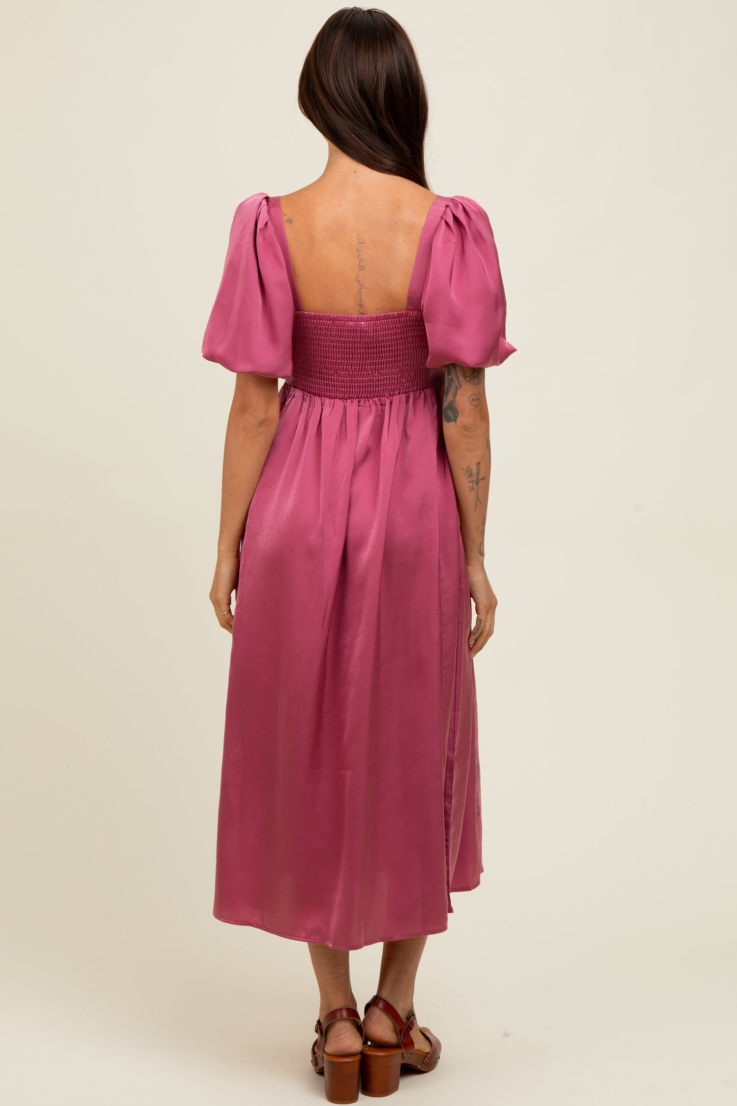 woman wearing a back view of a pink puff sleeve midi dress with a smocked bodice and a flowy skirt