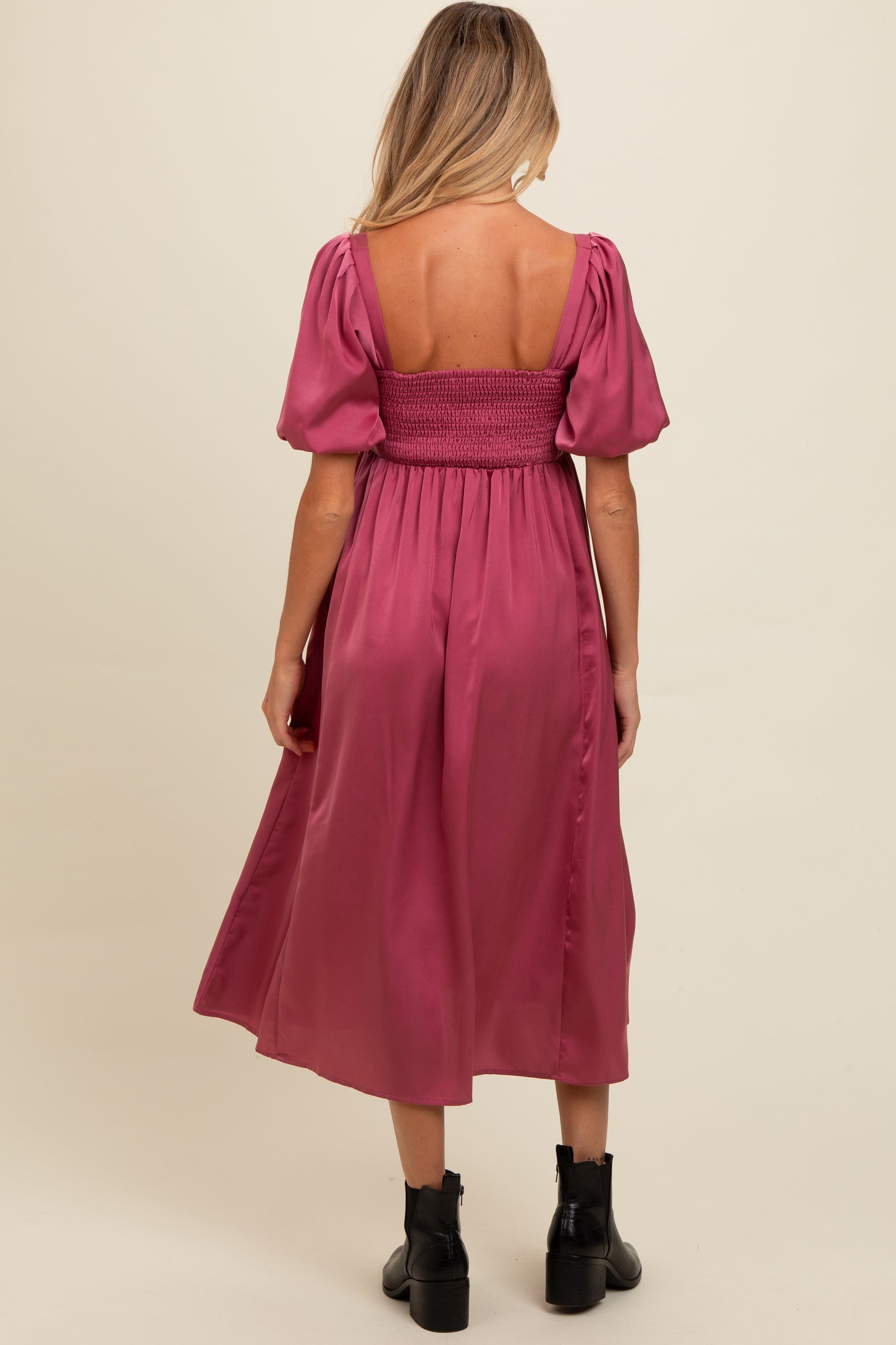 woman wearing a dusty pink maternity dress with puff sleeves and a smocked bodice, shown from the back