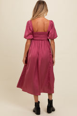 woman wearing a dusty pink maternity dress with puff sleeves and a smocked bodice, shown from the back