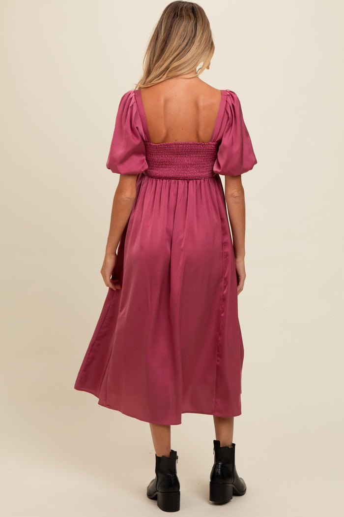 woman wearing a dusty pink maternity dress with puff sleeves and a smocked bodice, shown from the back