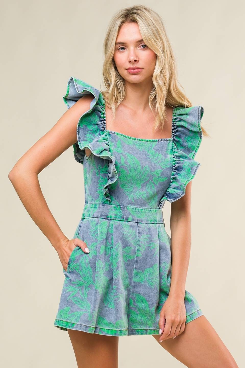 woman wearing a green and gray ruffled summer romper with a leaf pattern and pockets