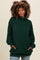 woman wearing a green oversized mock neck sweater with pockets and long sleeves