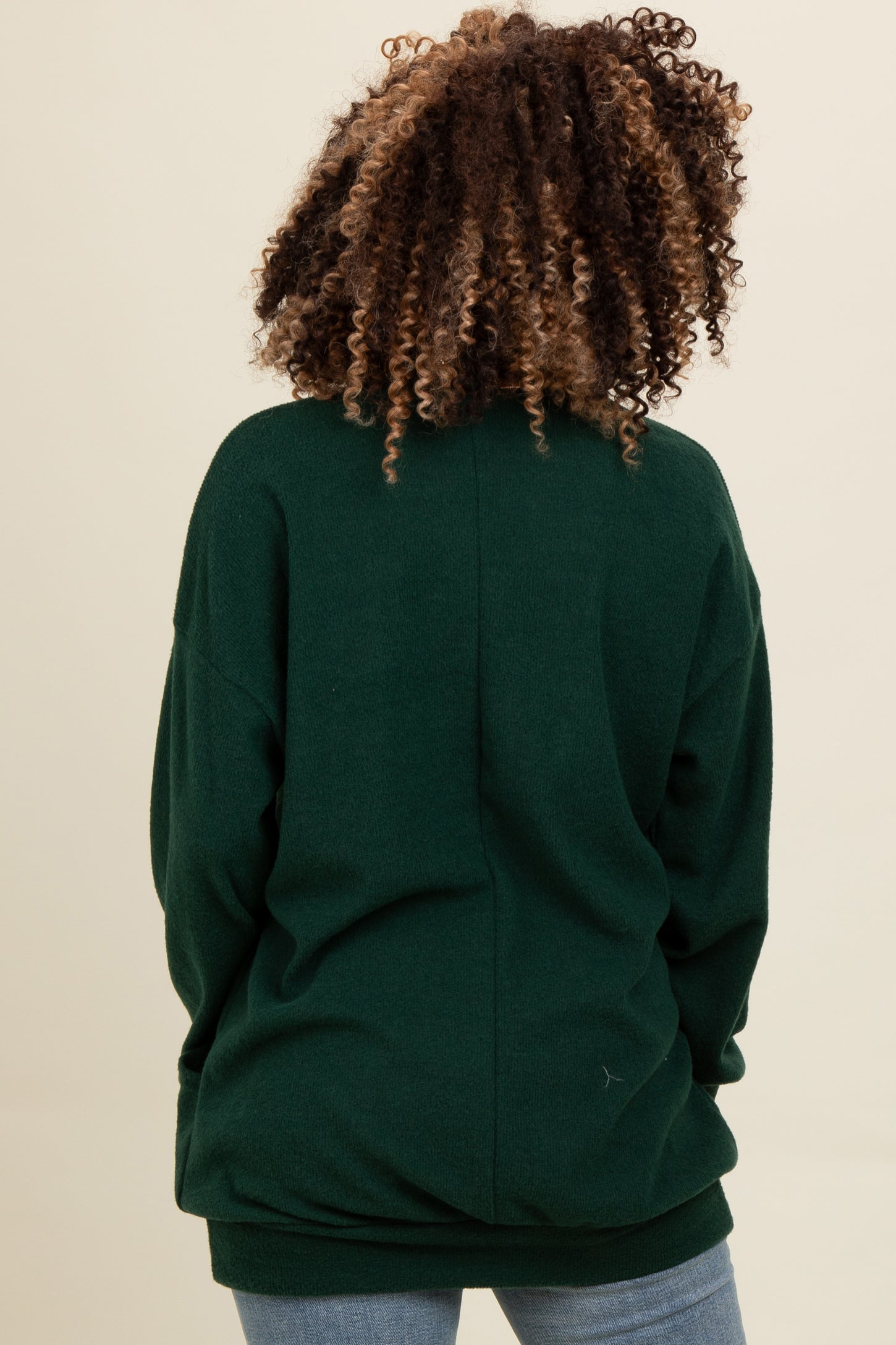 woman wearing a green oversized sweatshirt, back view, with curly hair and casual style