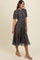 woman wearing a gray floral midi dress with short puff sleeves and a fitted waist