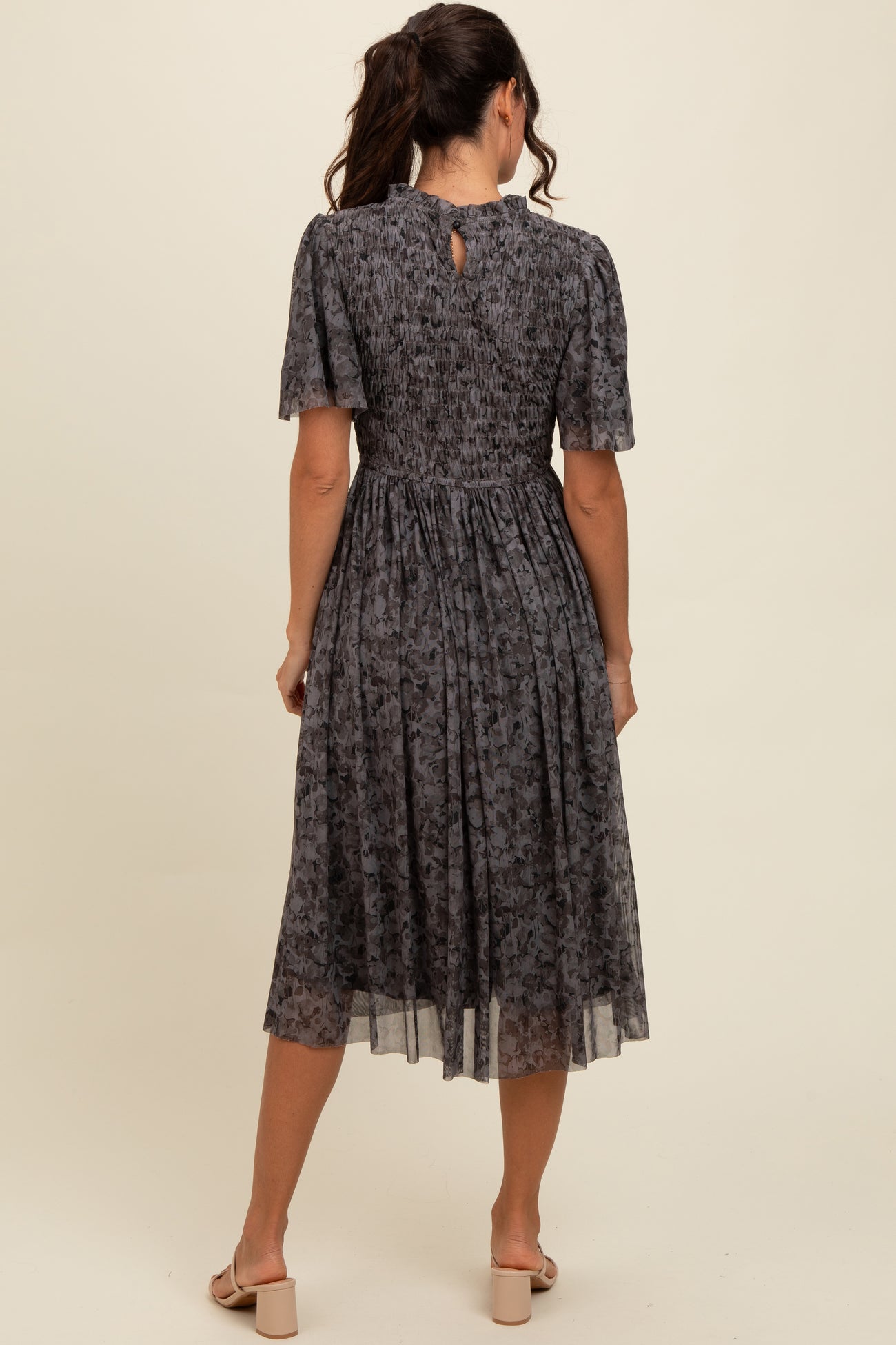 woman wearing a dark floral midi dress with short sleeves and a smocked back detail
