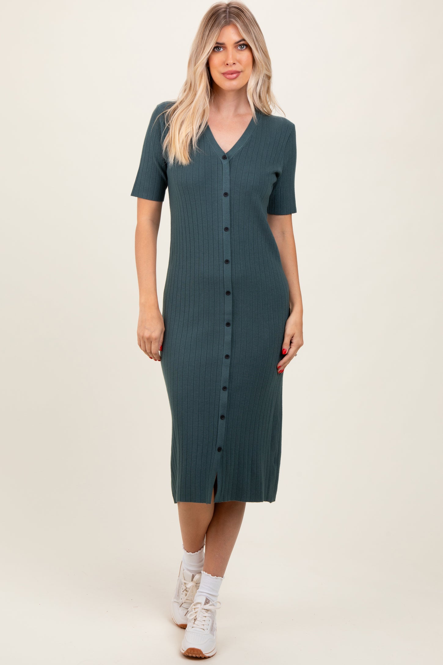 woman wearing a teal ribbed midi dress with short sleeves and button details, paired with white sneakers