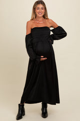 woman wearing a black off-the-shoulder maternity maxi dress and holding her baby bump