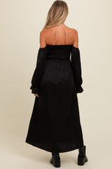 woman wearing a black off-the-shoulder maternity dress with long sleeves and a smocked bodice, showing a stylish back view
