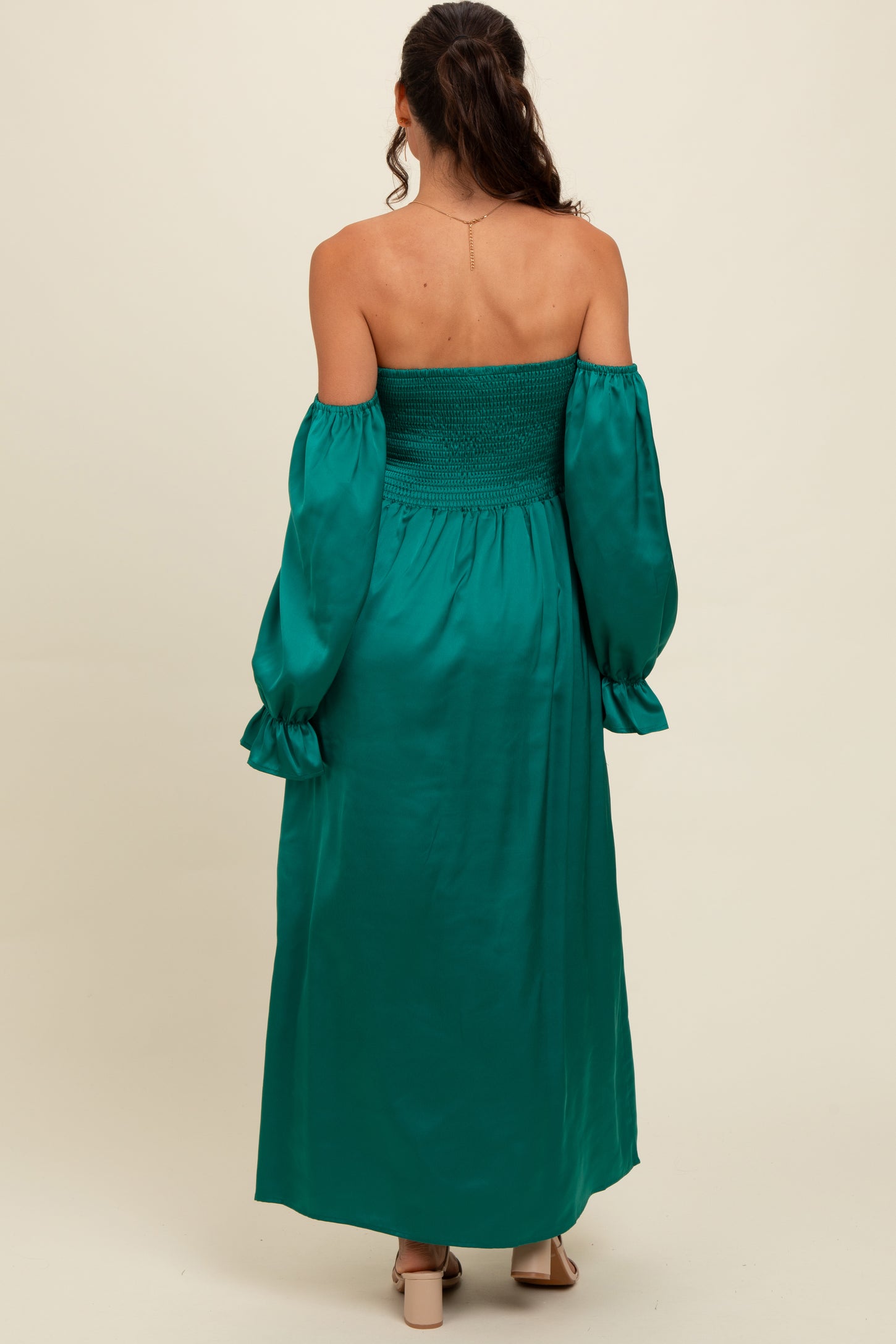 woman wearing a teal off-shoulder maxi dress with smocked bodice and puff sleeves, shown from the back