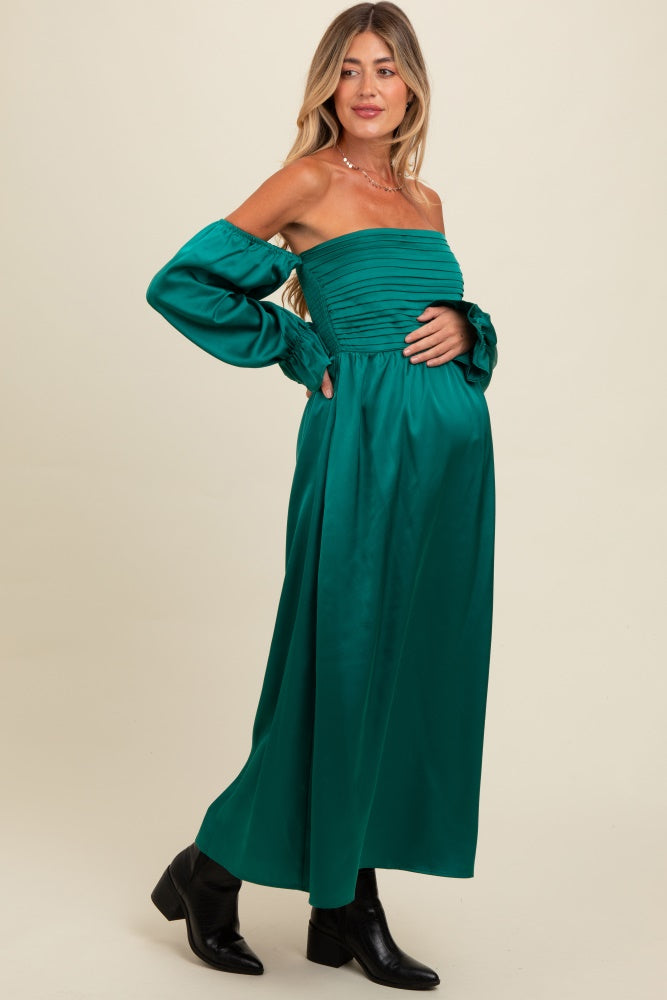 woman wearing a green off-the-shoulder maternity dress with ruffled sleeves and a visible baby bump