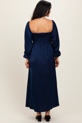 woman wearing a navy blue long sleeve maxi dress with a smocked bodice and a flowing skirt, shown from the back