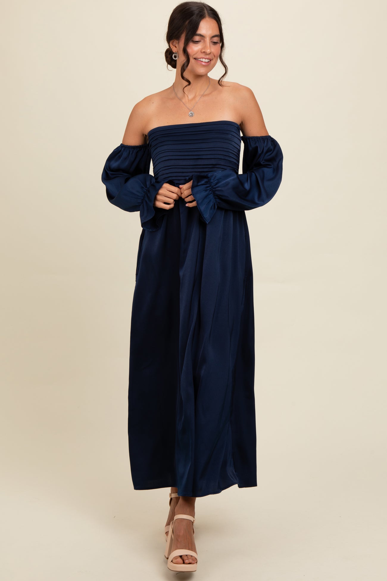 woman wearing a navy blue off-the-shoulder maxi dress with ruched bodice and puff sleeves, smiling and posing