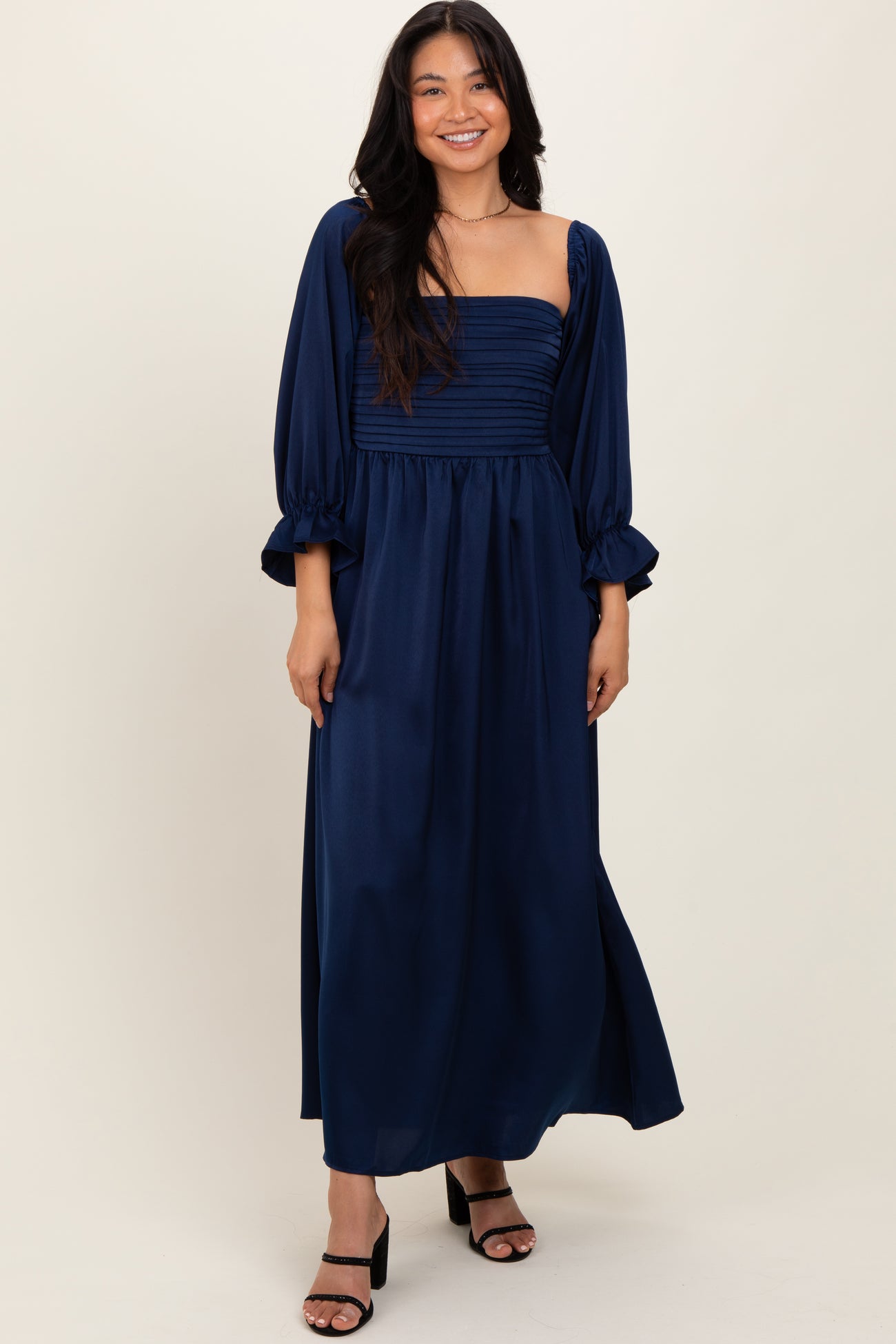 woman wearing a navy blue long sleeve maxi dress with a fitted bodice and puffed sleeves