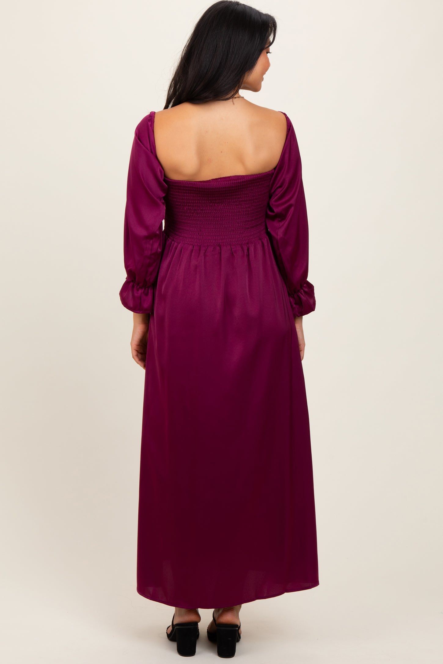 woman wearing a back view of a burgundy long sleeve maxi dress with smocked bodice and flowing skirt