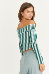 woman wearing a green and white striped off-shoulder long sleeve top with a fitted style and light blue pants