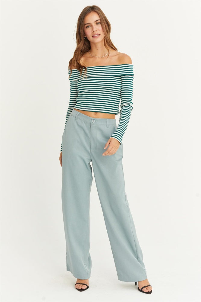 woman wearing a green and white striped off-the-shoulder crop top and light blue wide-leg pants