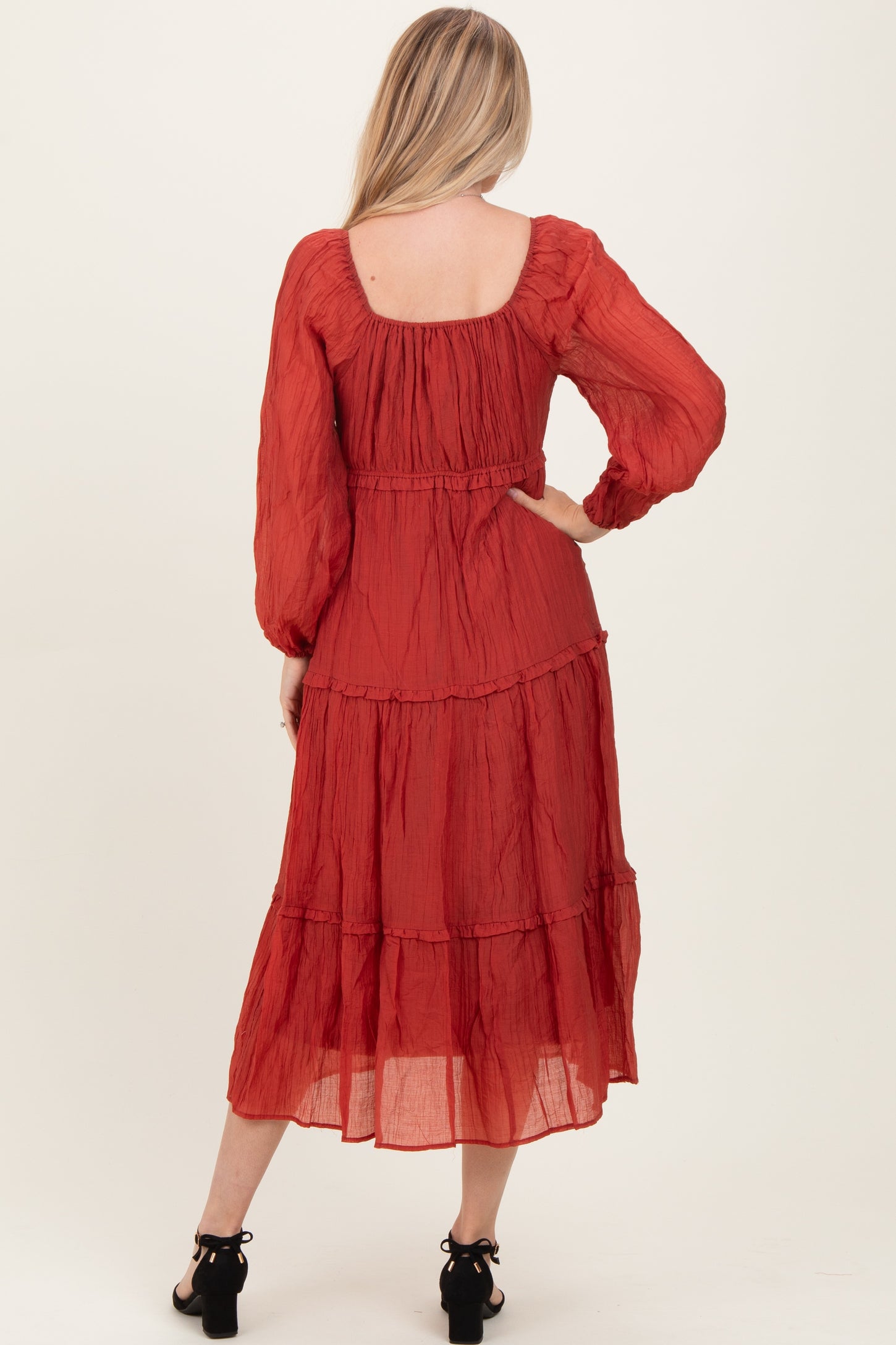 woman wearing a red tiered maxi dress with long sleeves, seen from the back