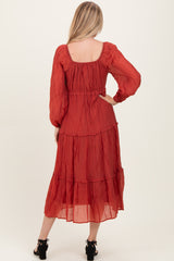 woman wearing a red tiered maxi dress with long sleeves, seen from the back