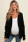 woman wearing a black knitted maternity cardigan over a white tank top and showing her baby bump