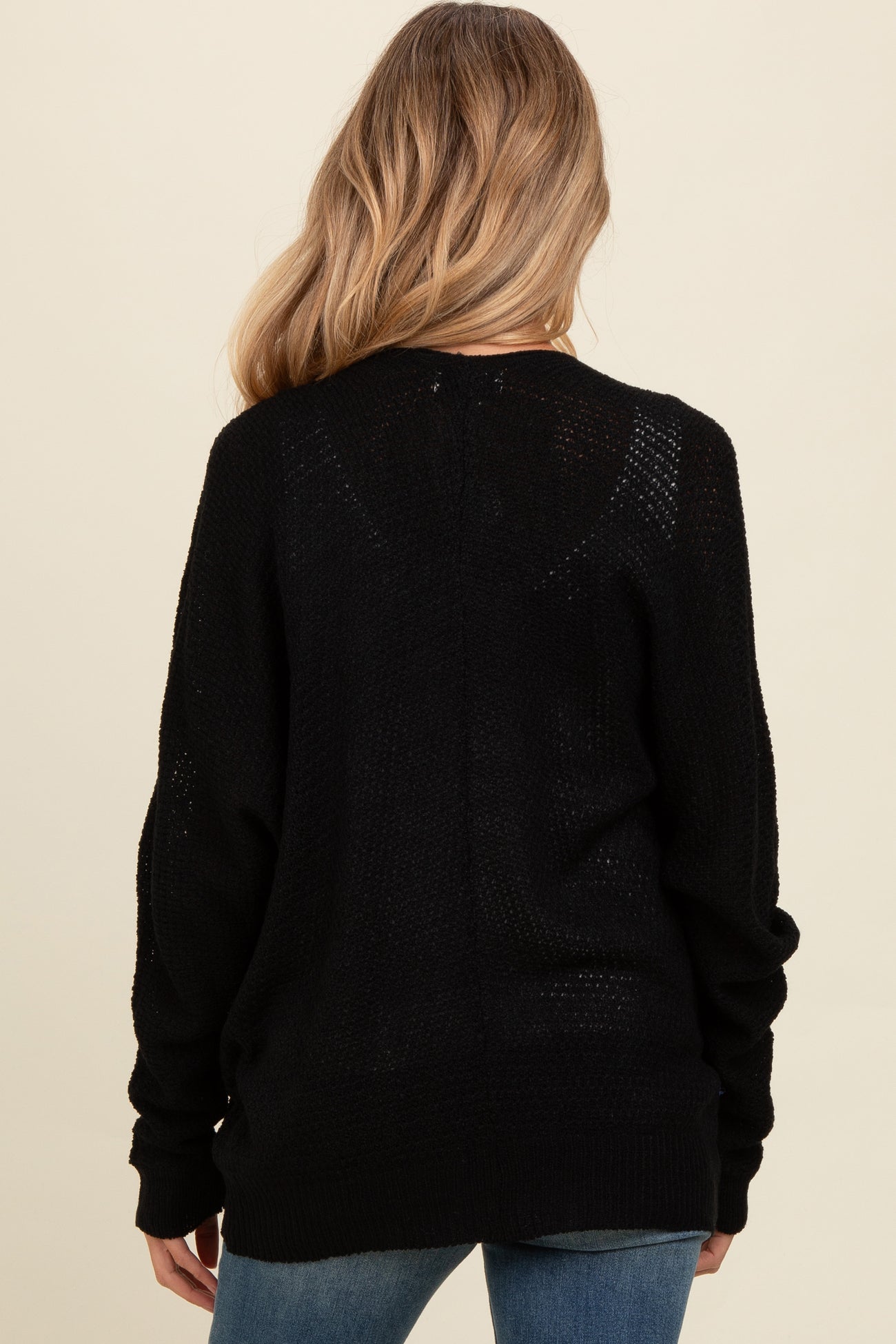woman wearing a black maternity sweater with loose knit details, view from the back