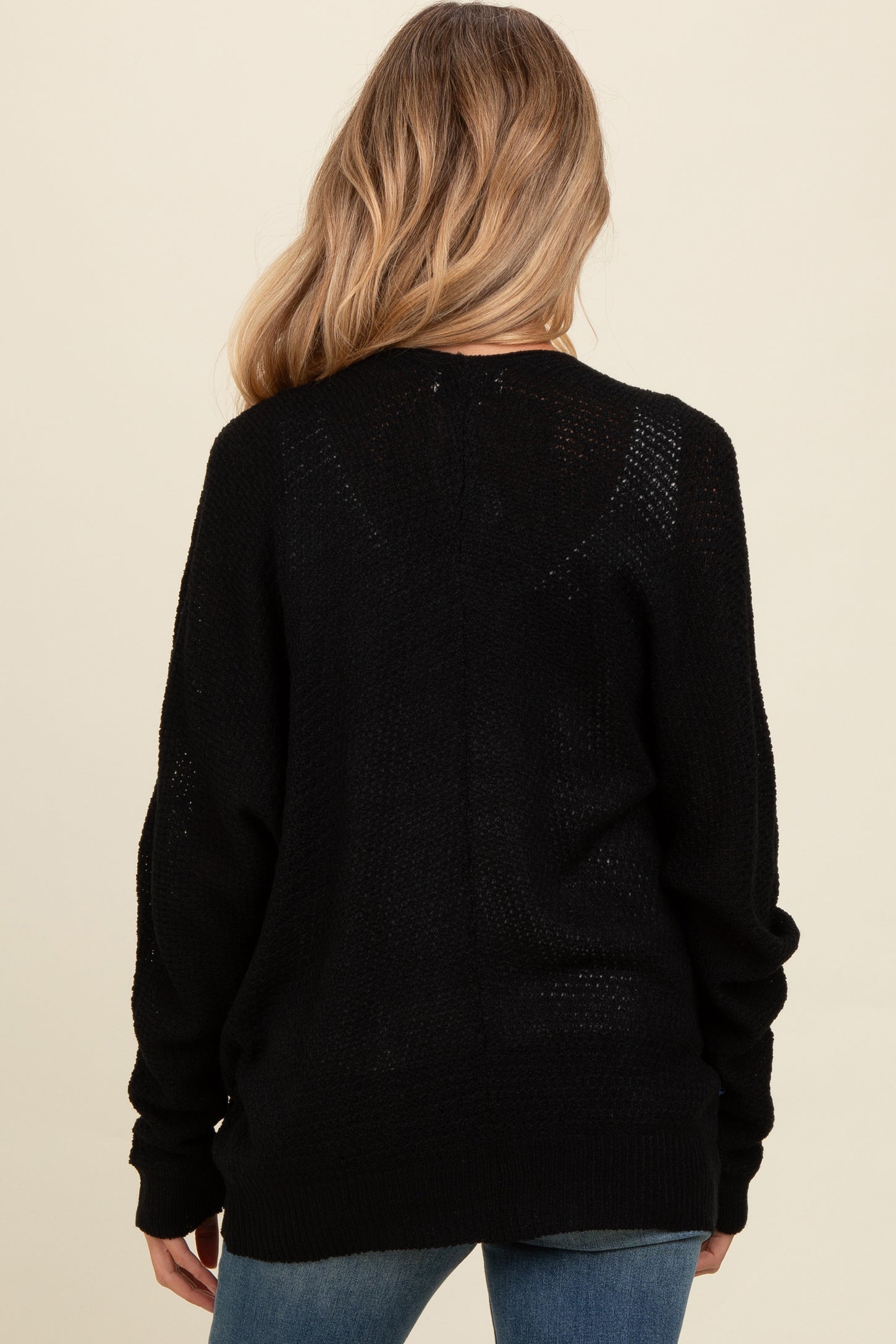 woman wearing a black maternity sweater with loose knit details, view from the back