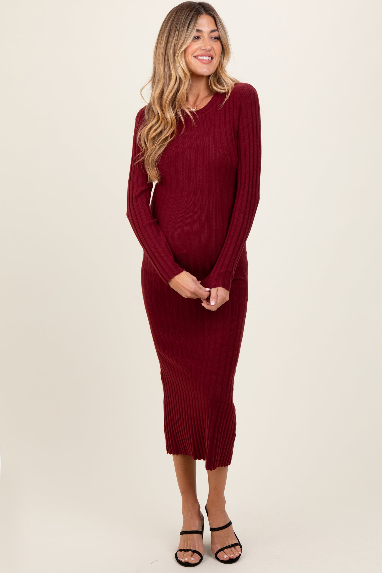 woman wearing a burgundy ribbed maternity dress with long sleeves and a fitted silhouette, showing her baby bump