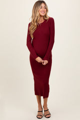 woman wearing a burgundy ribbed maternity dress with long sleeves and a fitted silhouette, showing her baby bump