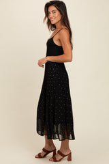 woman wearing a black spaghetti strap top and a black midi skirt with silver polka dots and pleats
