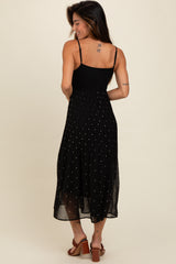 woman wearing a black midi dress with a fitted top and pleated skirt, featuring metallic dot embellishments