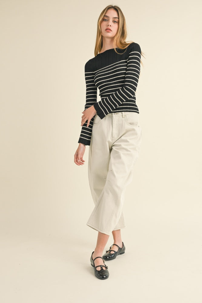woman wearing a black and white striped long sleeve top and loose cream wide-leg pants with black flats.