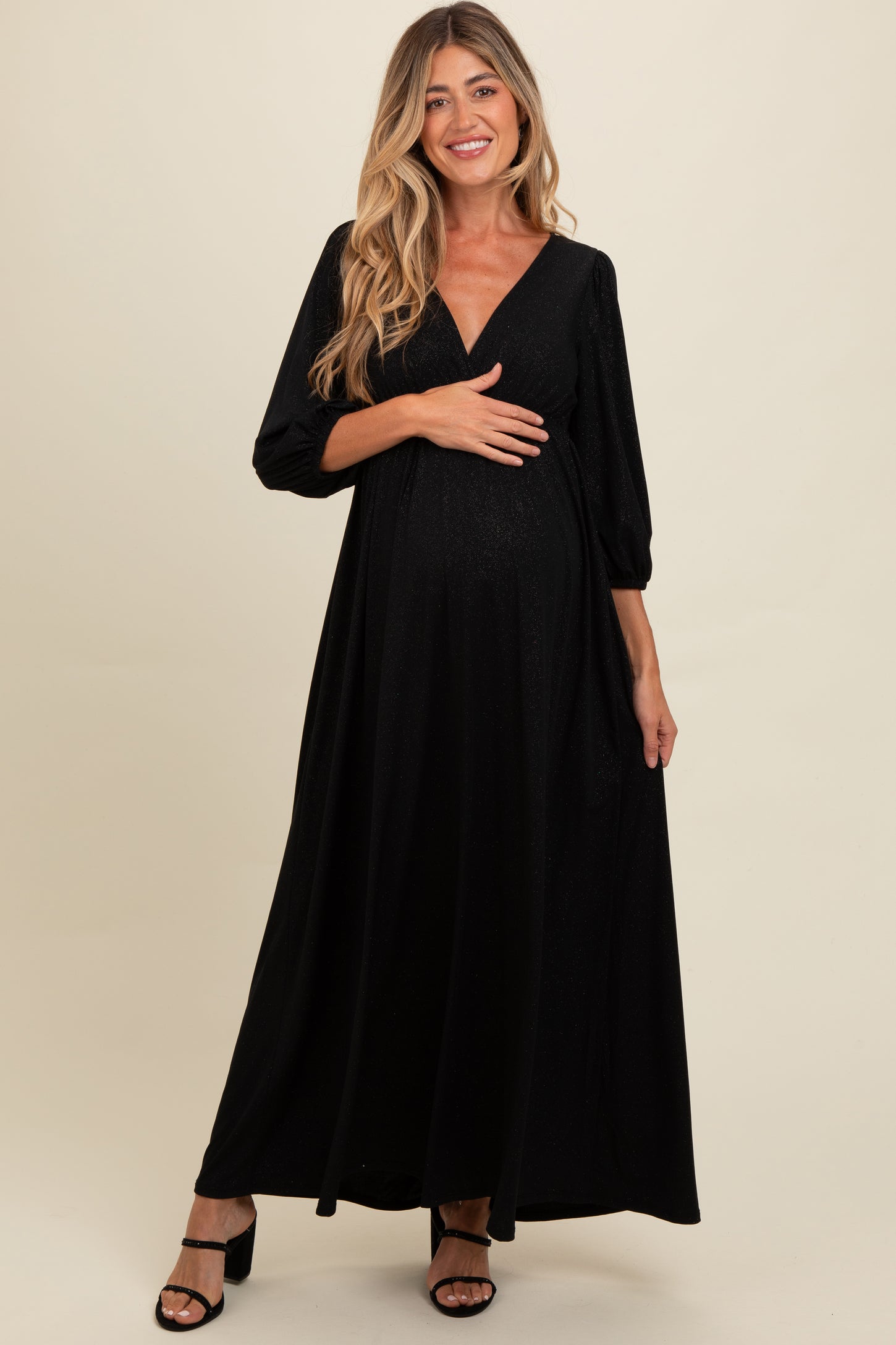 woman wearing a black maternity long sleeve maxi dress and holding her baby bump