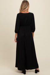 woman wearing a black sparkling maternity maxi dress with three-quarter sleeves and a high waist, showing a baby bump